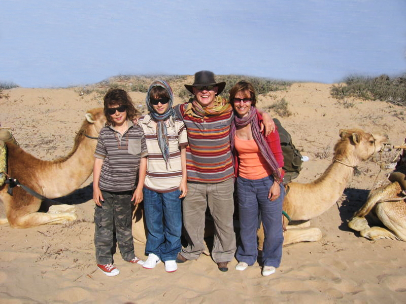 A family of four in front of a camel in the Moroccan Sahara desert