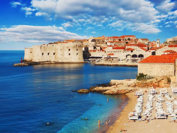 Aerial view of Dubrovnik, surrounded by water and filled with terracotta-roofed buildings