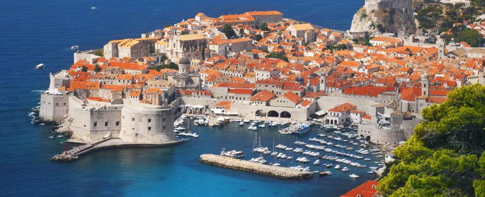 Aerial view of Dubrovnik, surrounded by water and filled with terracotta-roofed buildings