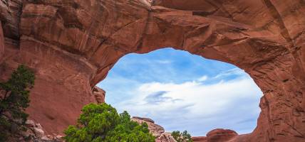 Female Hiker under Broken Arch, Arches National Park Utah - USA - North America Tours - On The Go To