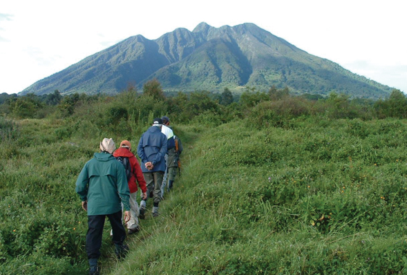 A group walking through Uganda with a mountain in the background